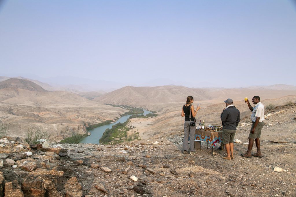 Drinks with tour guide on a hill overlooking a river while on an exclusive luxury safari experience in Kunene.