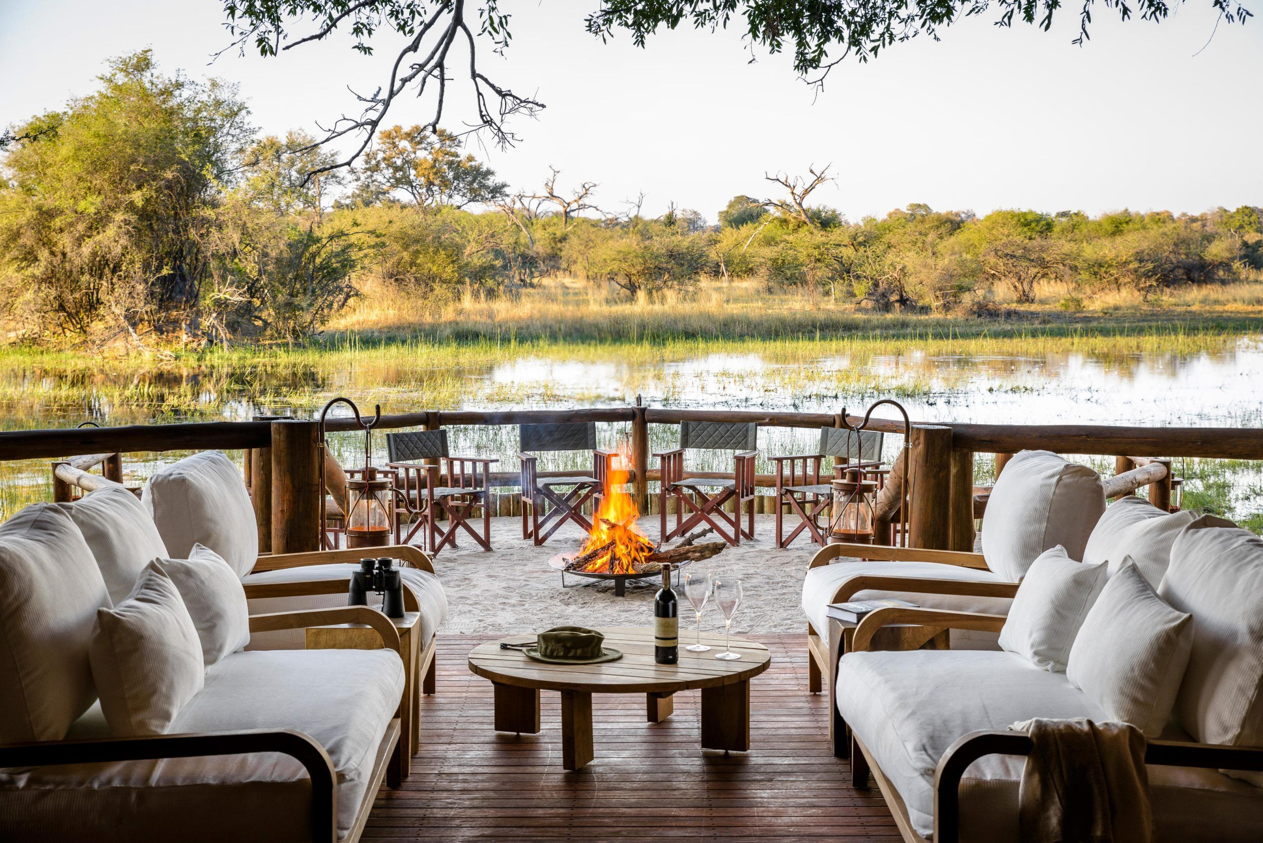 Relaxing at lunch time with wine at Camp Boma with river view and fire while on a luxury safari in Botswana.