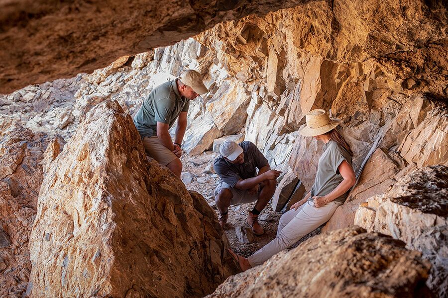 Private tour group looking at ancient cave art in the Sossusvlei, Namibia.